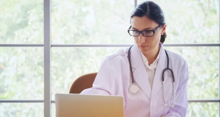 doctor-with-stethoscope-working-writing-on-paperwork-with-clipboard-and-laptop-computer-on-table-in_t20_P3bvJr (1)-1