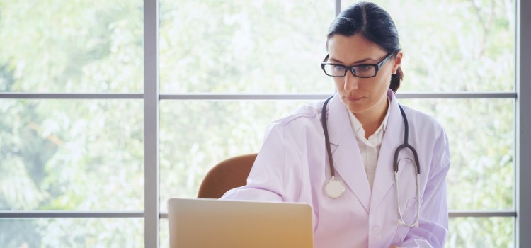 doctor-with-stethoscope-working-writing-on-paperwork-with-clipboard-and-laptop-computer-on-table-in_t20_P3bvJr (1)